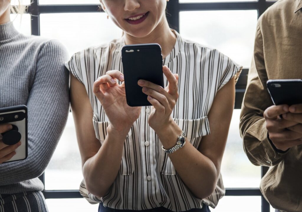 illustrative photo of a woman smiling and holding her cell phone