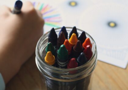 Kuvituskuva, jossa lapsen käsi ja värikyniä