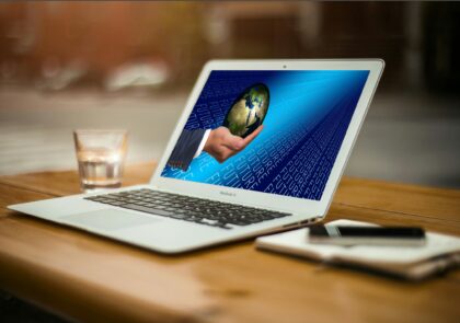 Kuvituskuva, jossa tietokoneen näytöllä näkyy maapallo ihmisen käden päällä