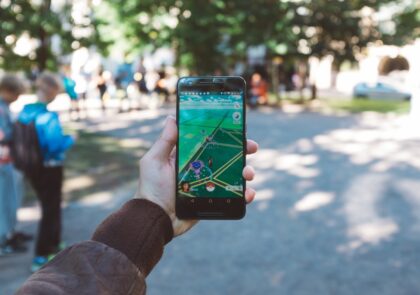 kuvituskuva, jossa henkilö pitää kädessään älypuhelinta jonka näytöllä pokemon go -peli