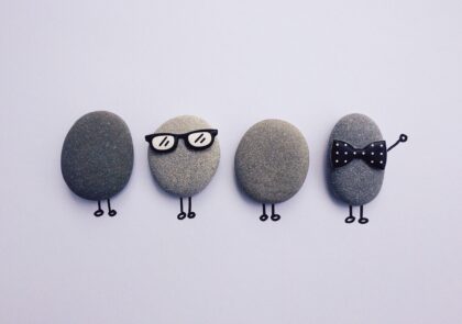 Kuvituskuva, jossa on neljä kivihahmoa, joista yhdellä silmälasit ja toisella rusetti.