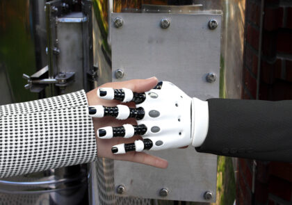 Kuvituskuva, jossa ihmisen ja robotin käsi kättelevät.