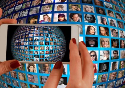 Kuvituskuva, jossa näkyvät kännykkää pitävät kädet ja taustalla kuvayhdistelmä ihmisten kasvoista