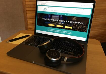 Kuvituskuvassa tietokone, jonka ruudulla näkyy artikkelissa esiteltävän konfrenssin pääsivu. Näppäimistön päällä on kuulokkeet.