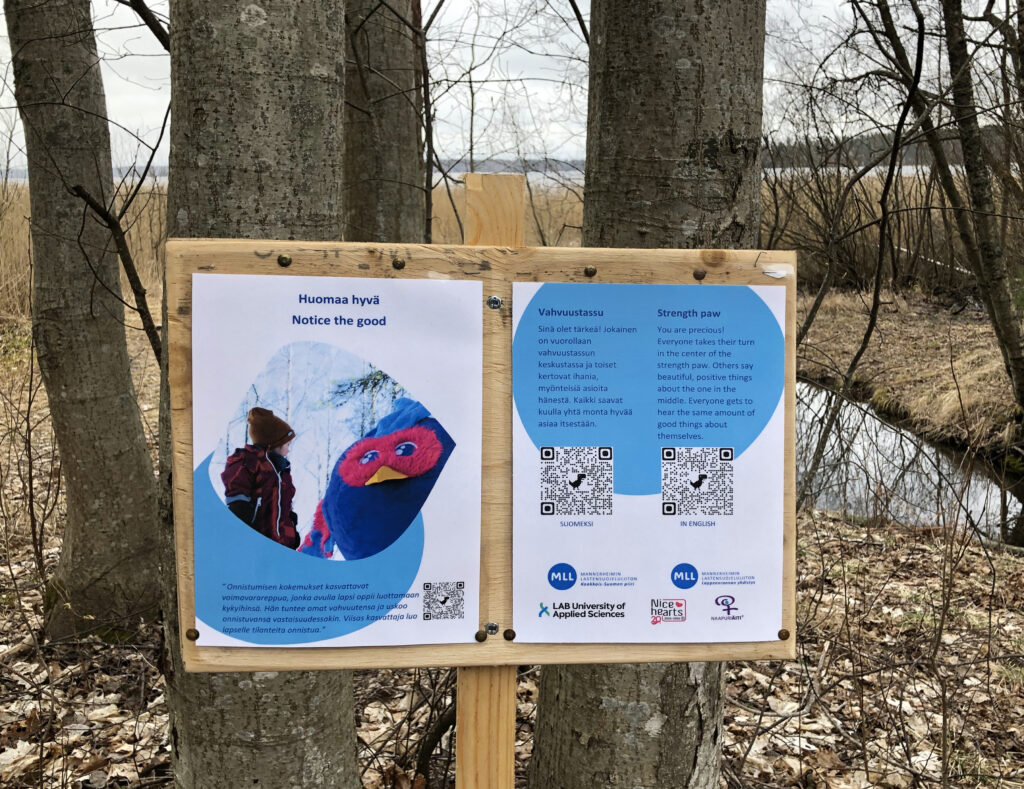 A wooden sign containing QR-tags that a passer-by can scan to access more information.