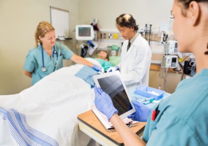 Kuvituskuvassa potilas makaa sairaalavuoteella ympärillään hoitohenkilökuntaa.