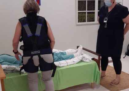 Kuvituskuvassa Auxivo liftsuit on apuna hoitotyössä, jossa kuormitus kohdistuu selälle erityisesti potilaan nostoon ja siirtämiseen liittyvissä tilanteissa.