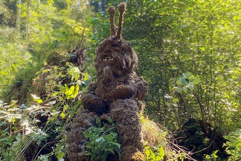 Grumpy moss creature sitting in a sunny spot in the forest.