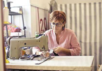 A photograph of a woman sewing or repairing on a sewing machine.
