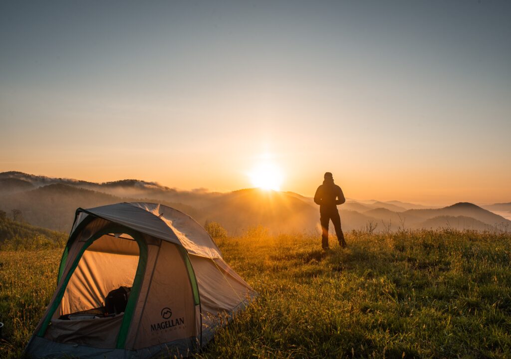 Nature traveler watching the sun behind hills.