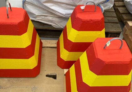 Punaisella ja keltaisella huomiomaalattua betonisia liikenne-esteitä.