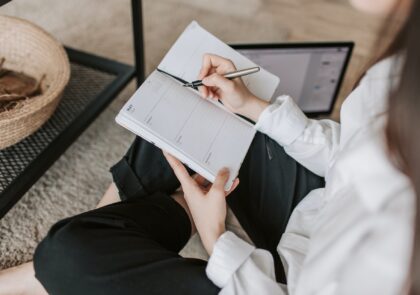 Nainen istuu sohvalla ja kirjoittaa päiväkirjaa.