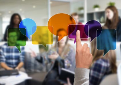 Kuvituskuvassa on taustalla ryhmä ihmisiä ja edessä värikkäitä, tyhjiä puhekuplia.