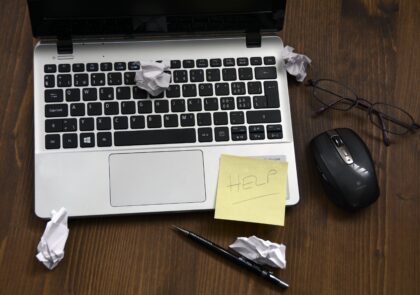 Kuvituskuva kannettavasta tietokoneesta jonka ympärillä on rypistettyjä papereita ja lappu jossa lukee help