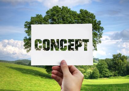 -Kesäinen niitty ja etualalla käsi, joka pitää concept-kylttiä.