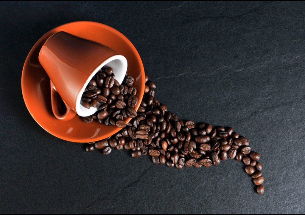 Illustration shows coffee beans on an orange ceramic mug.