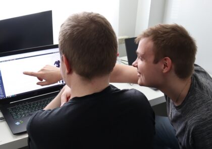 KuvituskuvIstuvassa kaksi ihmistä istuu tietokoneen ääressä. Toinen osoittaa jotain ruudulta, jota molemmat katsovat.