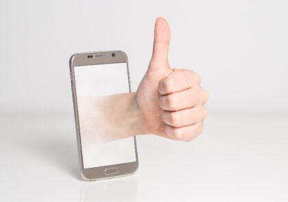 Kuvituskuvassa kännykkä ja käsi, joka näyttää peukkua,
