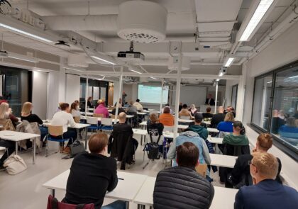 Kuvituskuvassa ihmisiä istumassa luokassa seuraamassa esitystä.