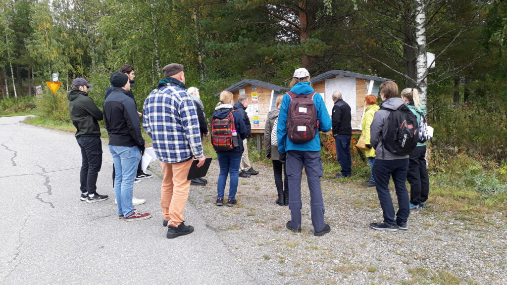 Young students and older teacher and members of the village community discussing about climate risks outside.