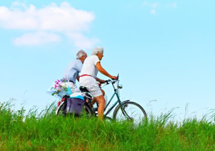 Kuvituskuvassa kaksi iäkästä ihmistä pyöräilee.