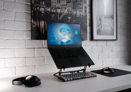 Kuvituskuvassa kannettava tietokone, jonka näytöllä näkyy kuva aivoista ja teksti AI.