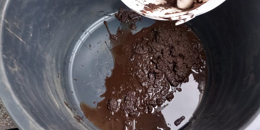 Mustan saavin pohjalla on ruskeaa materiaalia, joka koostuu kiinteästä ja nestemäisestä osuudesta