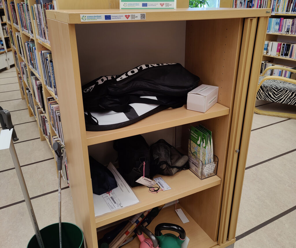 Kaappi, jossa on urheiluvälineitä, kuten kahvakuulia sekä sulkapallo- ja padelpelivälineet, lainattavaksi.