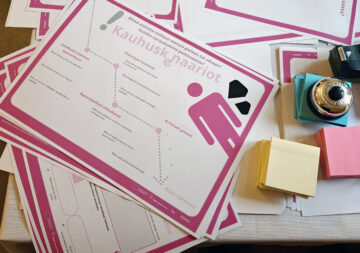 Pöydällä eri värisiä muistilappuja, soittokello sekä kauhuskenaariot-työpohja, jossa teemat yhteistyön riskien arviointiin: asiakkaan kokema epävarmuus, yhteistyön haasteet, konkreettiset uhkakuvat ja kriittiset pisteet.