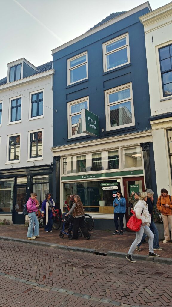 Ihmiset odottavat kadulla noutopisteen aukeamista